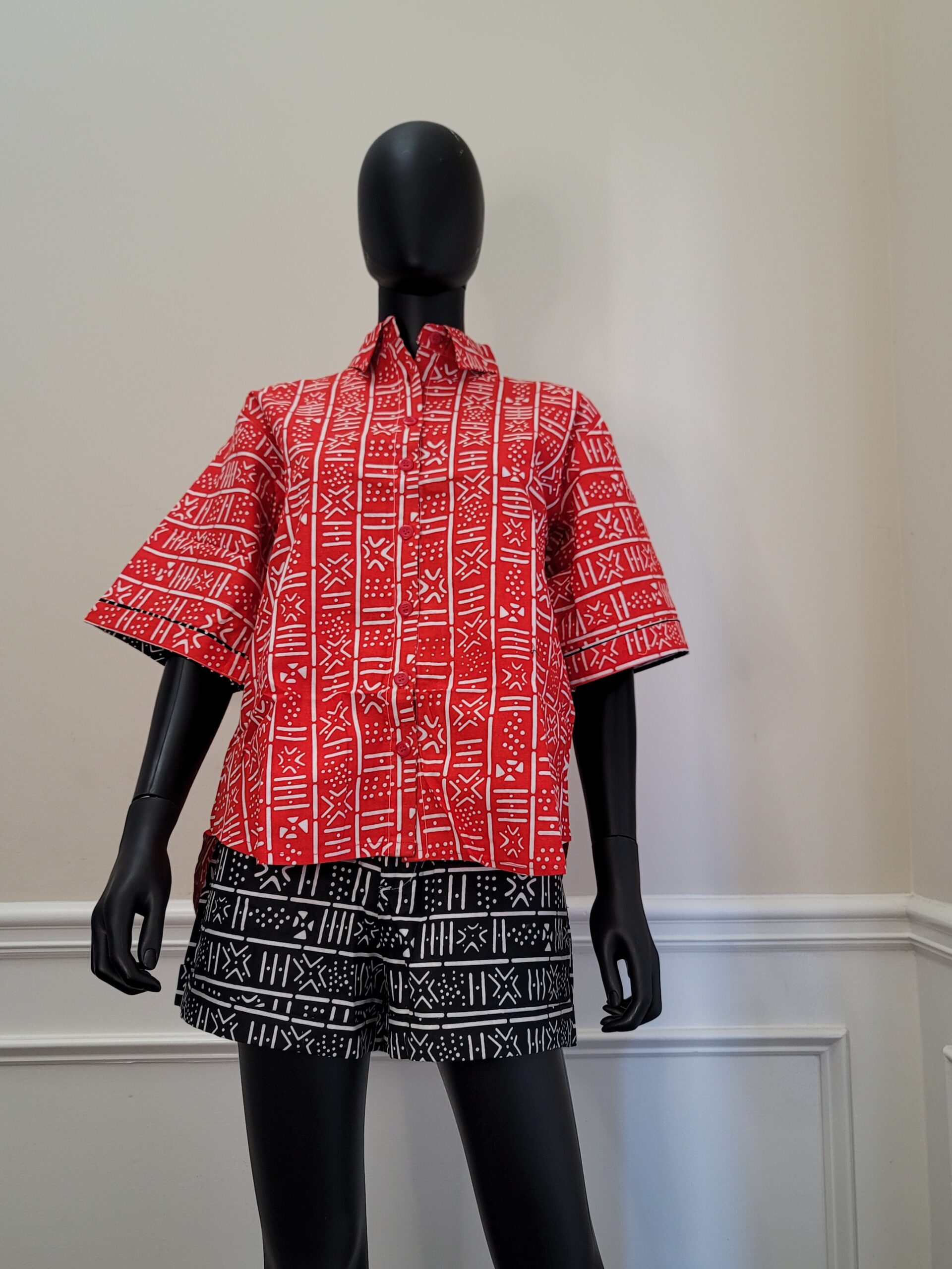 African two-piece short sleeve shorts set. Shirt is red with white tribal patterns. Shorts are black with white tribal patterns.